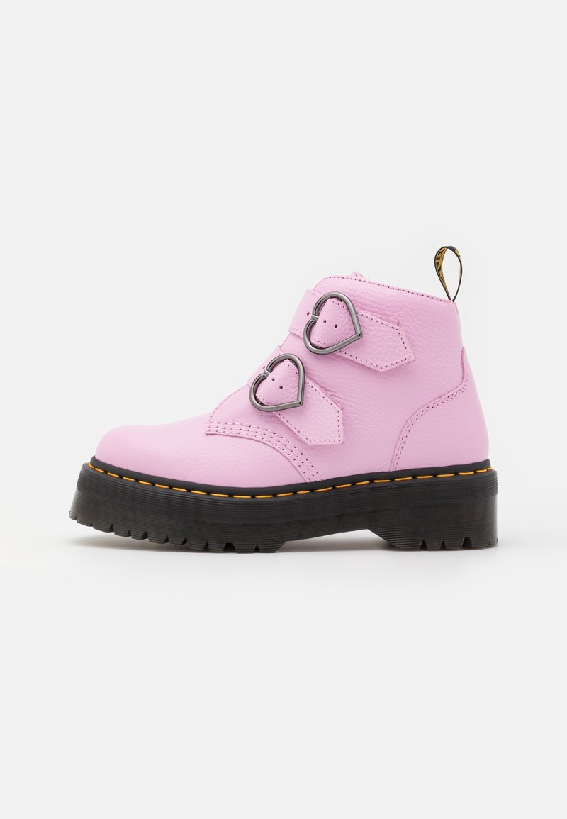 Bottine en cuir rose avec deux boucles argentées en forme de cœur et semelle noire épaisse avec coutures jaunes.