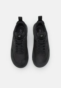 Sorte atletiske sko med en glat læderoverdel, tekstureret tåspids og polstret pløs. Har snørebåndsdesign og en træksløjfe ved hælen.