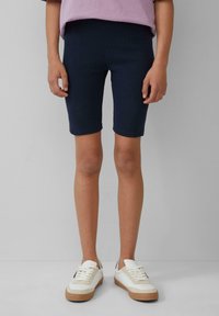 Navyblauwe geribbelde fietsshorts van rekbare katoen, gecombineerd met witte sneakers met een beige zool en accenten.