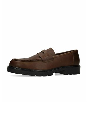 Bruine leren loafer met dikke zwarte rubberen zool en mocassin-stijl stiksels, gezien van opzij tegen een witte achtergrond.
