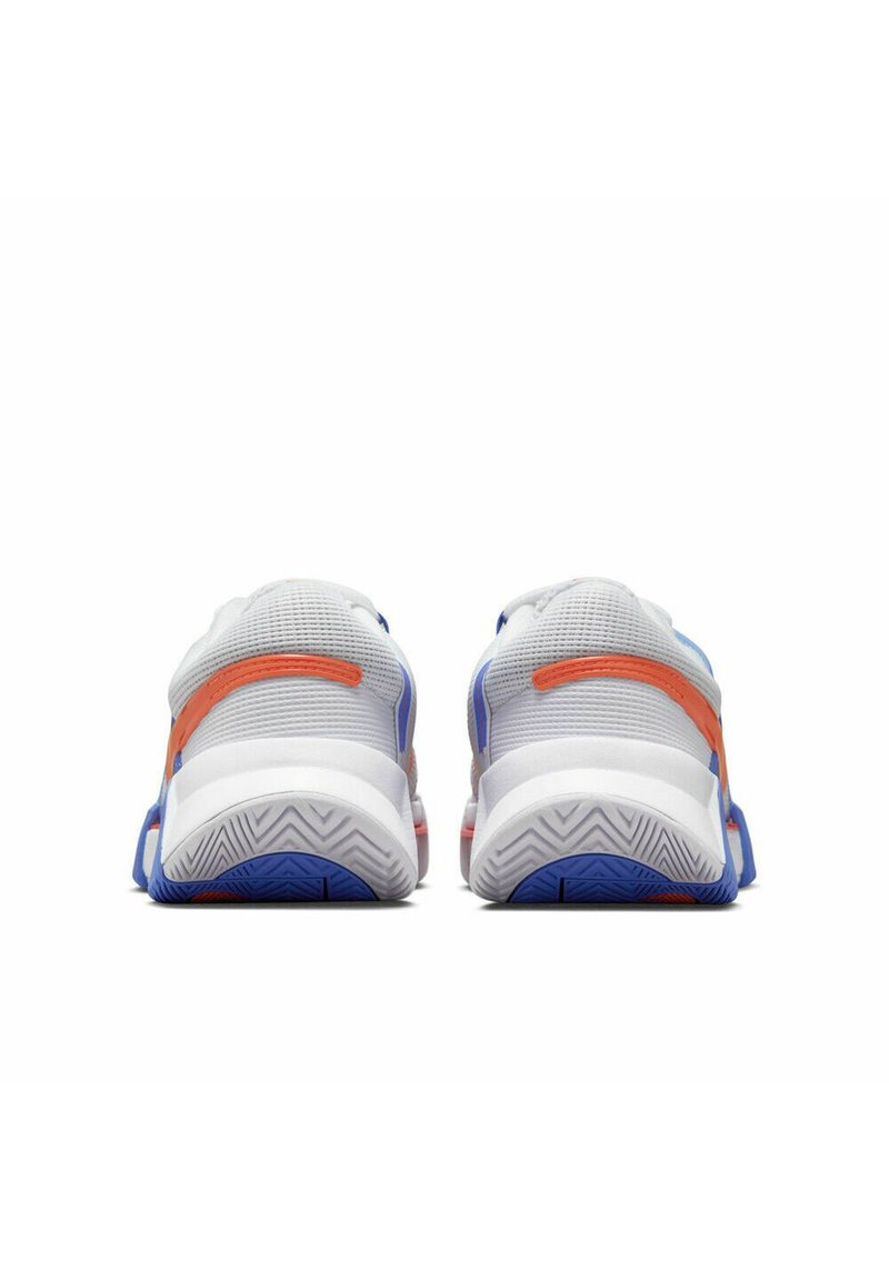 Tył widoku sportowych butów z białej siateczki z pomarańczowymi i niebieskimi akcentami. Charakteryzuje się teksturowaną podeszwą o zygzakowatym wzorze. Okrągły kształt i wyściółka w okolicy kostki.