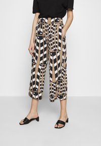 Cropped trousers with a geometric pattern in beige, black, and white; features side pockets, high waist, and a relaxed fit.