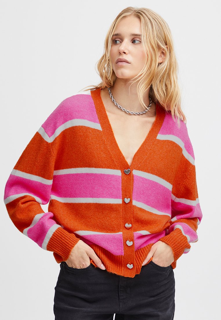 Jasno kolorowy kardigan w paski w odcieniach pomarańczowym, różowym i jasnoszarym. Posiada głęboki dekolt w serek oraz guziki w kształcie serca z przodu. Miękka tekstura.