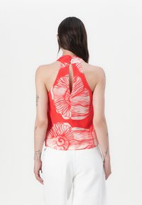 Red halter top featuring a floral print with a keyhole detail at the back. Made of lightweight fabric with smooth texture.