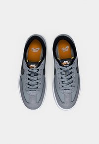 Nike SB Classic joggesko i grå mesh og semsket skinn, med snøring, en polstret innleggssåle i oransje og svarte detaljer på hælen og tungen.