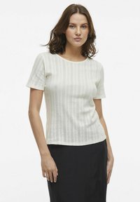 Wit T-shirt met korte mouwen, voorzien van gestructureerde verticale strepen en eenvoudige patronen. Ronde halslijn, aansluitend ontwerp en zachte breisels.