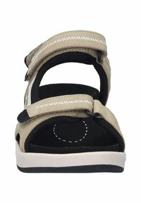 Beige sandaalit, joissa on kaksinkertaisesti säädettävät velcro-nauhat, pehmeä musta pohja, valkoiset tikkaukset ja kevyt pohja mustilla yksityiskohdilla.