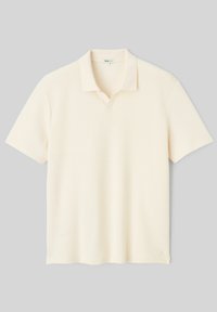 Polo crème à manches courtes avec un col souple et un léger décolleté en V, posé à plat sur un fond gris clair.