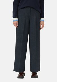 Wijde donkerblauwe pantalon met krijtstrepen en een nauwkeurige snit. Draagt onder een marineblauwe trui en glanzende bordeauxrode schoenen. Glad textuur en gestructureerd ontwerp.