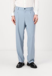 Light blue tailored trousers with a smooth texture, featuring front pleats and a button closure, paired with black shoes.
