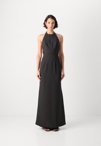 Črna maxi obleka s halter izrezom, prilegajočim se bodijem in tekočim krilom. Gladek material, minimalistična zasnova, brez vidnih vzorcev ali okrasitev.