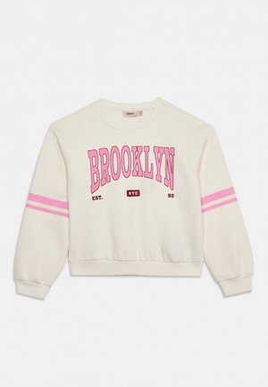 Sweat-shirt crème avec des rayures roses sur les manches et une grande inscription rose « Brooklyn » sur le devant.