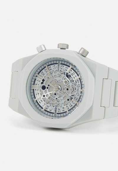 Λευκό οκταγωνικό ρολόι με διαφανή σκελετωτή διάταξη, ασημένιες λεπτομέρειες και λουράκι σιλικόνης. Διαθέτει λειτουργίες χρονογράφου και ενδείξεις.