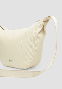 Cremfarbene perforierte Lederhandtasche mit runder Form, ausgestattet mit einem Reißverschluss und einem flachen, gewebten Schulterriemen. Inklusive silberner Hardware-Akzente.