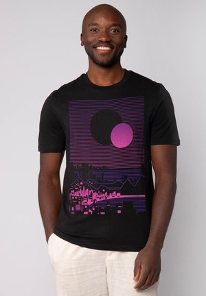 Zwart katoenen t-shirt met een grafisch ontwerp in paars en roze, dat geometrische vormen en een skylinepatroon afbeeldt. Korte mouwen, ronde hals.