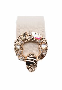 Fibbia circolare color oro con pietre multicolori su una fascia in tessuto beige. Presenta motivi testurizzati e un accento ovale centrale.