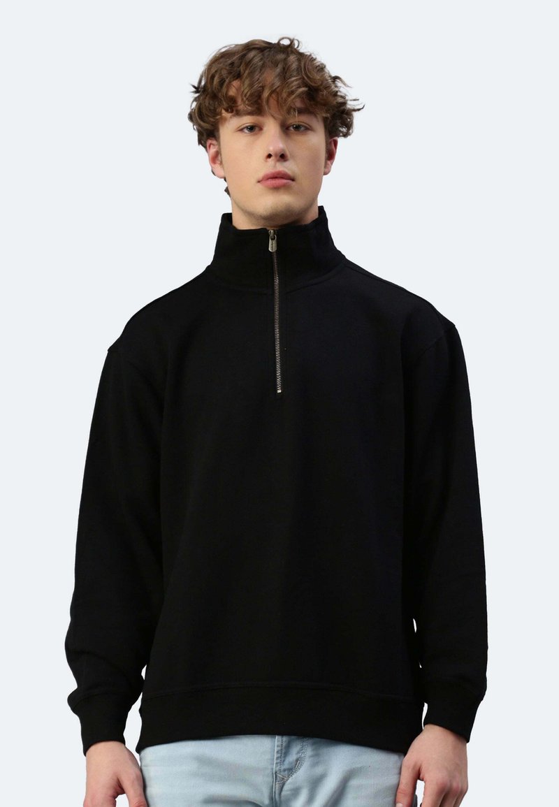 Schwarzer Pullover mit hohem Kragen, halbem Reißverschluss vorne und gerippten Bündchen. Weicher Stoff mit lockerer Passform und ohne sichtbare Muster.