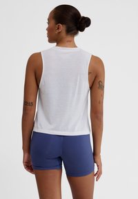 White, sleeveless tank top with a round neckline, paired with fitted blue shorts. The fabric appears lightweight with a smooth texture.