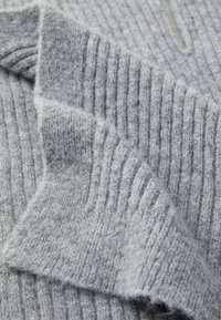 Close-up of soft, gray knit fabric with vertical ribbing, showcasing the texture and gentle folds in the material.