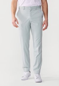 Pantaloni gri deschis, cu tăietură ajustată, confecționați dintr-un material neted, cu un design frontal simplu. Purtați cu adidași albi pentru un aspect casual.