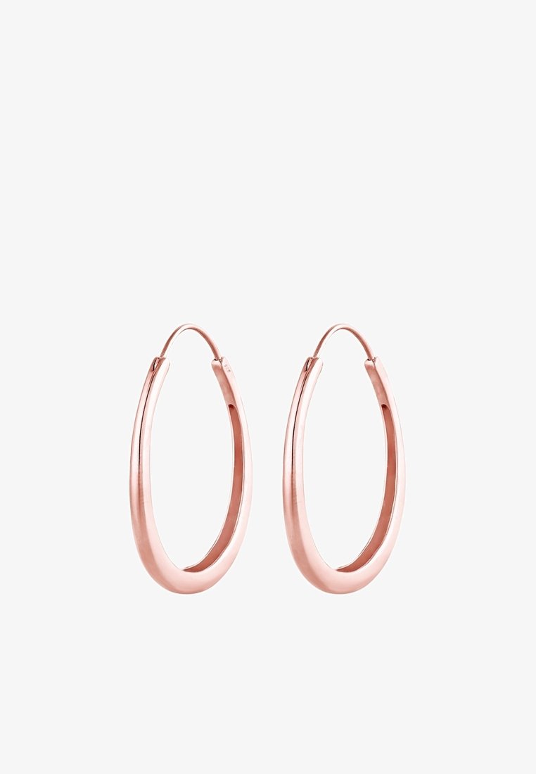 Paire de boucles d'oreilles créoles allongées en or rose poli avec une forme ovale lisse et légèrement épaissie sur fond blanc.