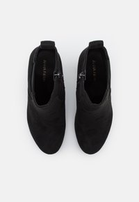 Svarta mockaankelboots med dragkedja och strukturerad ovandel, med låg klack och rund tådesign.