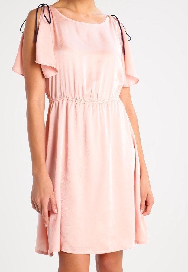 Robe rose clair à manches courtes avec un col arrondi, une taille élastique et des manches volantées. Présente des liens bleu marine au niveau des coutures des épaules. Matière satinée.