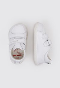 Chaussures en cuir blanc avec deux bandes Velcro, bout arrondi, accents texturés et semelle en caoutchouc légère. Taille indiquée comme 21 à l'intérieur.