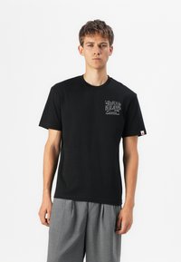 Black cotton t-shirt with short sleeves and round neckline, featuring a graphic print on the left chest and a small label on the right sleeve.