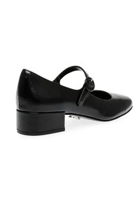 Scarpa in pelle verniciata nera con punta tonda, tacco basso a blocco e una cinghia decorativa con fibbia circolare. Texture liscia e design elegante.