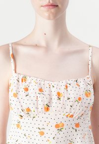 Rochie roz deschis cu buline negre mici și modele florale portocalii. Prezentând bretele subțiri și un corset texturat, plisat.