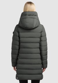 Roheline puffer-tuulejope, millel on kapuuts, horisontaalne triibuline muster ja küljetaskud. Materjal näib sile ja läikiv.