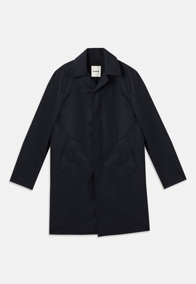 Ναυτικό παλτό με γιακά σε σχήμα V, μονόπετο σχέδιο, δύο πλαϊνές τσέπες και απαλό ύφασμα. Μινιμαλιστικό στυλ, χωρίς ορατά μεταλλικά στοιχεία.