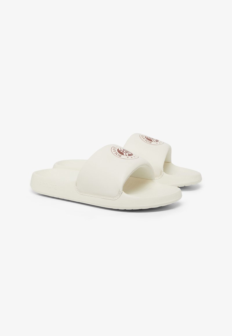 White slide sandals featuring a wide strap with a logo, soft textured material, and a flat sole. Minimalist design and smooth finish.