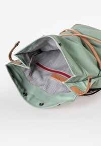 Grün wasserfester Beutel mit Akzenten aus braunem Leder. Das Innere hat ein kariertes Muster, eine rote Reißverschlusstasche und ein Markenetikett.