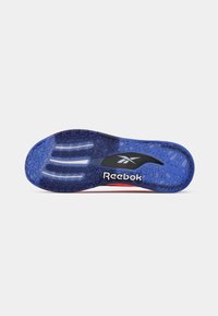 Sola de sapato Reebok, apresentando uma superfície de borracha azul com padrão, detalhes brancos e marcação preta. Texturizada para aderência e durabilidade.