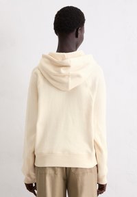 Crème-kleurige hoodie gemaakt van zachte katoen, met een grote capuchon, geribbelde manchetten en een relaxte pasvorm met ingezette mouwen.