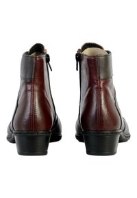Bottines en cuir marron et noir, avec un petit talon, fermeture éclair sur le côté et des détails de couture le long de la semelle. Texture lisse et design ajusté.