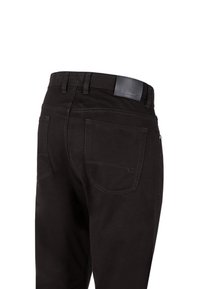 Czarne dżinsy o gładkiej fakturze, z naszywką na pasie, dwiema tylnymi kieszeniami oraz kontrastowymi detalami w szwach.