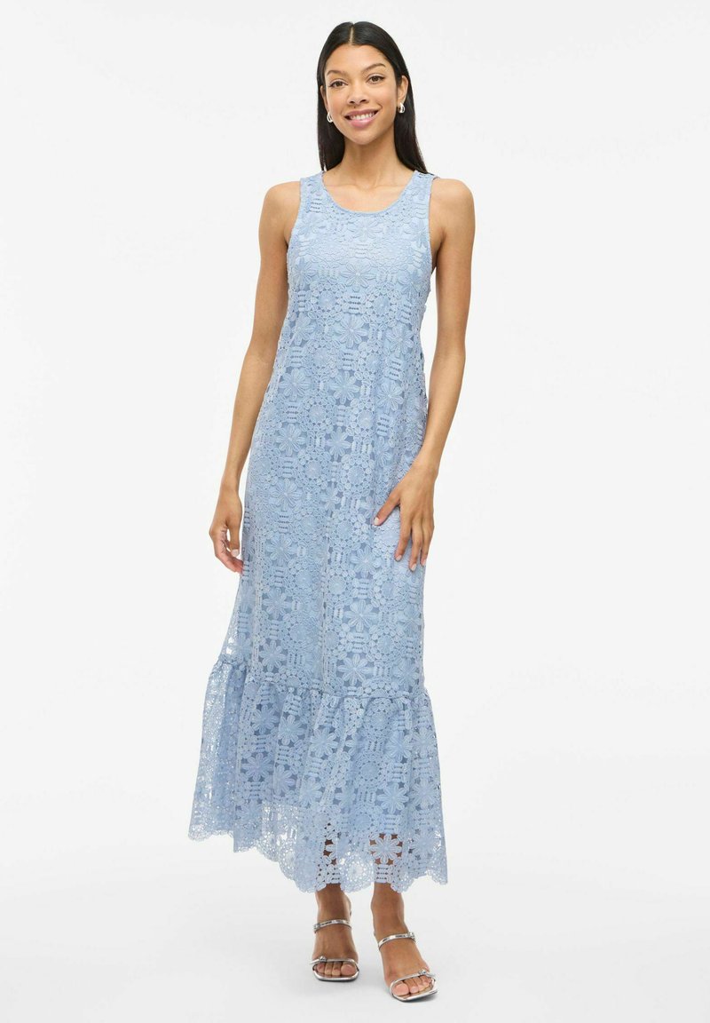 Light blue, sleeveless maxi dress made of lace with floral patterns, featuring a ruffled hem and a fitted bodice. Transparent texture is evident.