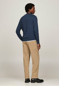 Maglione blu navy a maniche lunghe in morbido tessuto a maglia, abbinato a pantaloni khaki. Stivali neri con suola spessa completano l'outfit. Vestibilità casual, vista posteriore mostrata.
