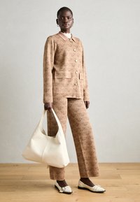 Strukturierter brauner Anzug mit einem taillierten Blazer, weitem Hosenbein und einer cremefarbenen Handtasche. Enthält ein weißes Hemd mit Kragen und flache Schuhe.