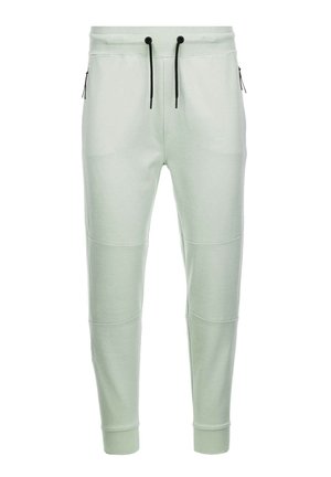 Lys grønne joggers i blødt materiale med elastisk talje og snøre, tapered ben og lynlåslommer på siderne. Glat tekstur med paneldetaljer.