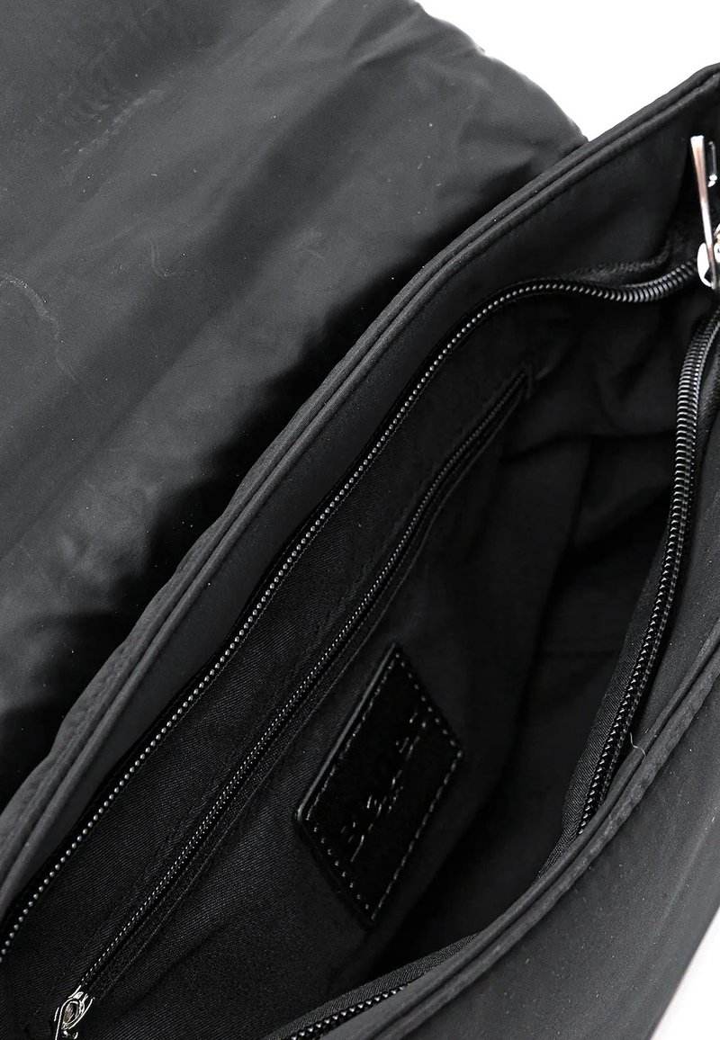 Borsa di stoffa nera aperta per mostrare l'interno con una tasca con cerniera e un'etichetta nera all'interno.