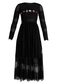 Robe noire à manches longues en tissu transparent avec broderie florale sur le buste. Dispose de détails en dentelle et d'un ourlet à franges multicouches.