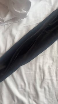Un tessuto di velluto nero si distende su una superficie bianca, mostrando una texture liscia e una forma slanciata ed elegante. Nessun motivo o accessorio visibile.