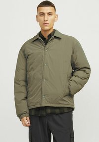 Puffer jacket in olive green, featuring a collared design, snap-button front, side pockets, and ribbed cuffs for added warmth and comfort.