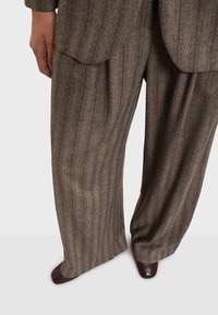 Pantaloni di lana grigi con un sottile motivo a spina di pesce e righe bordeaux. Design a gamba larga con pieghe frontali e tasche laterali.