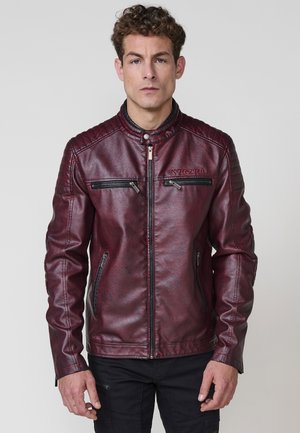 Chaqueta de cuero sintético burdeos con collar alzado, acentos acolchados en los hombros y múltiples bolsillos con cremallera en la parte frontal.