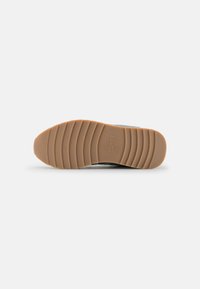 Sneaker with a textured gray upper and rubber outsole. Features a light brown ridged pattern providing grip. Simple design, no prominent accents.